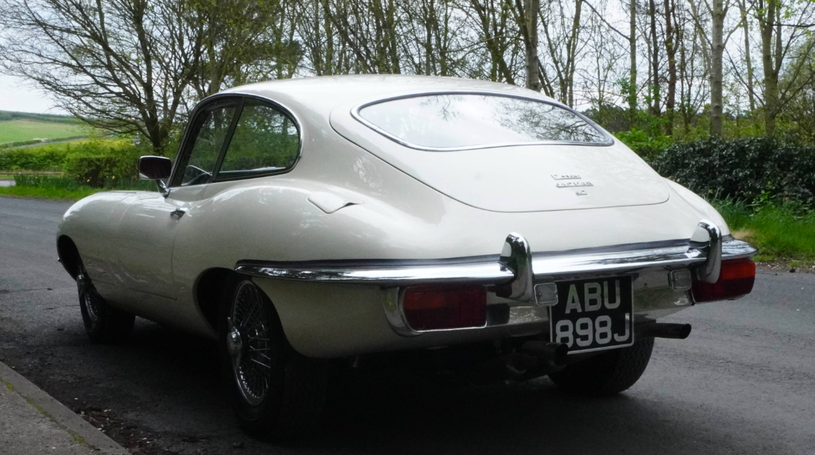 A white Jaguar E-Type fixed-head coupe, registration ABU 898J, seen from the rear three-quarter