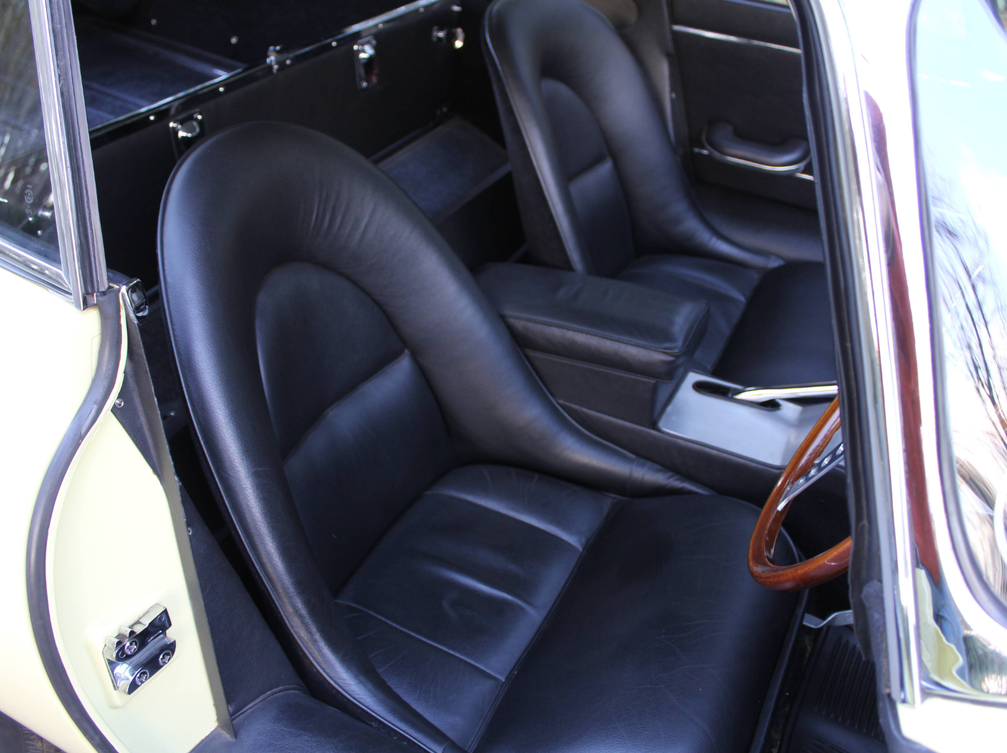Black leather bucket seats and door card inside a Series 1 E-Type fixed-head coupe
