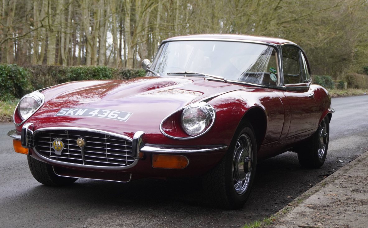 A red Series 3 Jaguar E-Type fixed-head coupe, registration SKN 436J, parked at the roadside