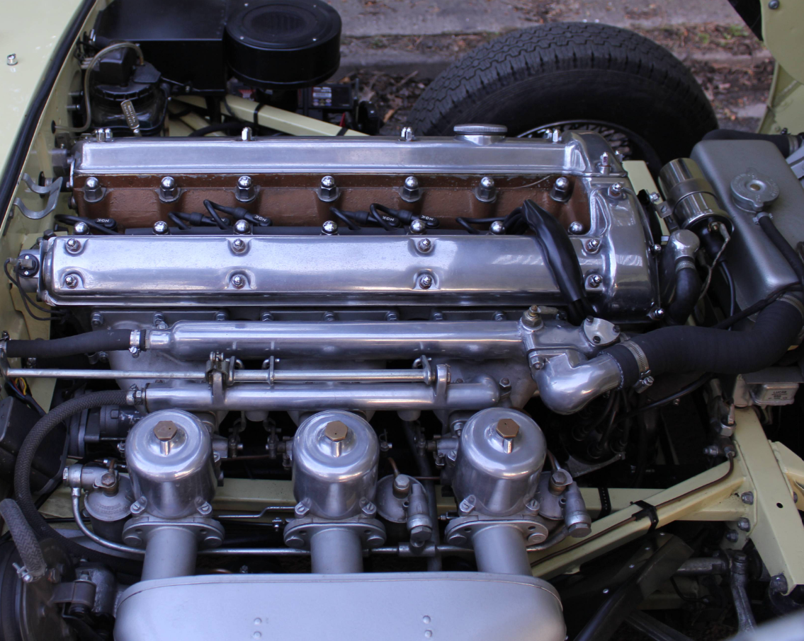 The 3.8-litre XK straight-six in a pale green E-Type engine bay, with triple SU carburettors and a polished cam cover