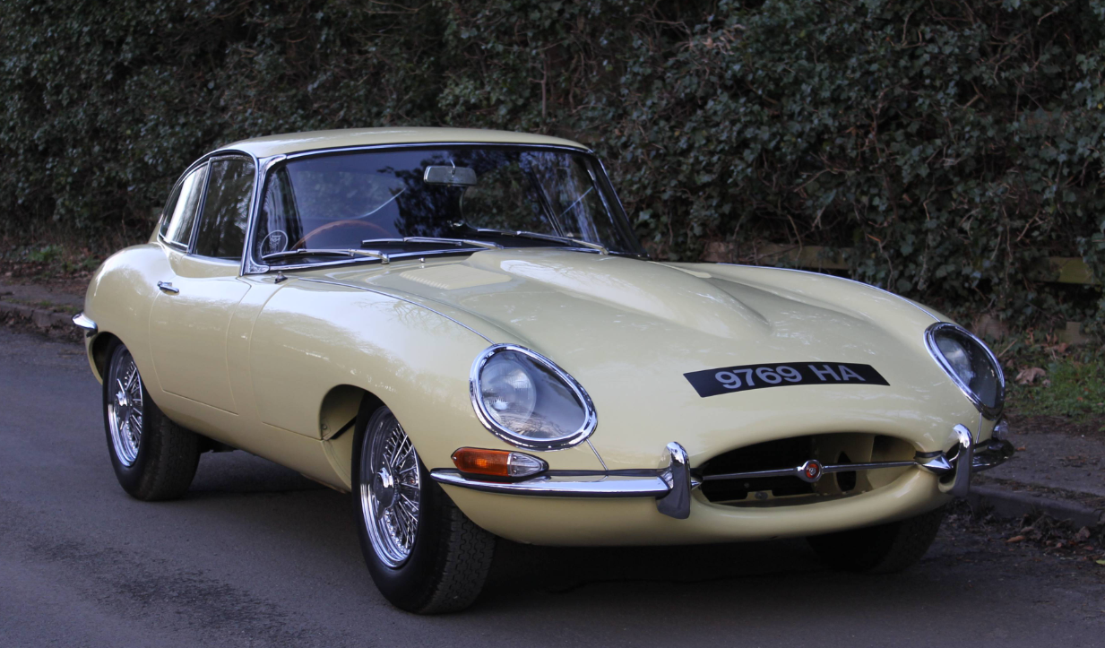 Front three-quarter view of a Primrose 1963 Jaguar E-Type Series 1 3.8 fixed-head coupe registered 9769 HA