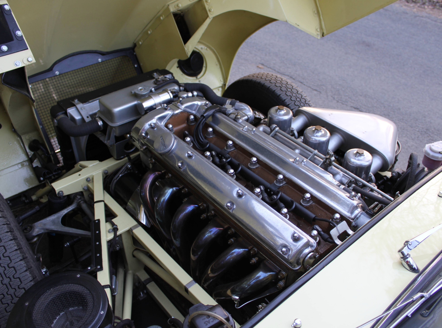 Front view into the E-Type engine bay showing the six-branch exhaust manifold, radiator and front frames