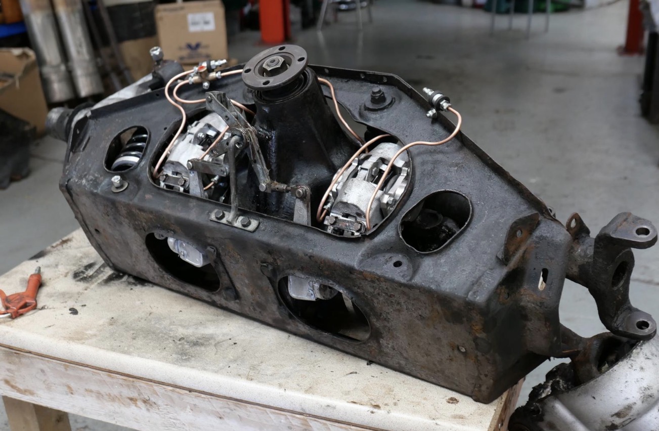 Jaguar E-Type rear suspension cage removed from the car, with the inboard brake calipers visible and copper remote bleed lines fitted